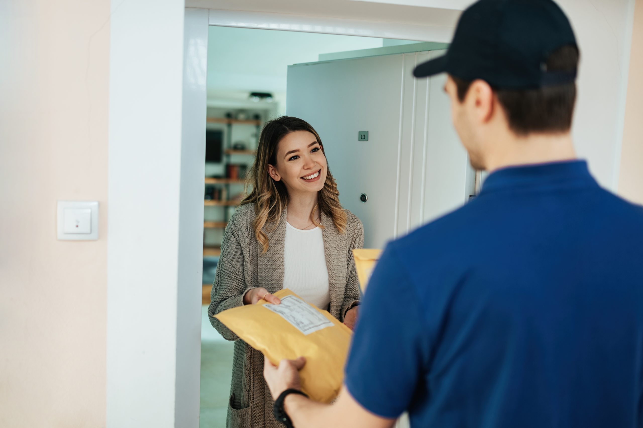 mujer feliz tomando el paquete de un mensajero mientras recibe la entrega domicilio scaled